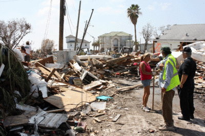 Photo of people standing in a street surrounded by debris.