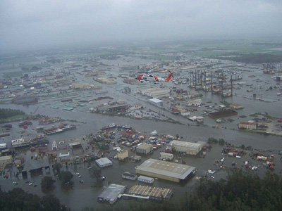 A US Coast Gaurd helicopter flying over a flooded city.