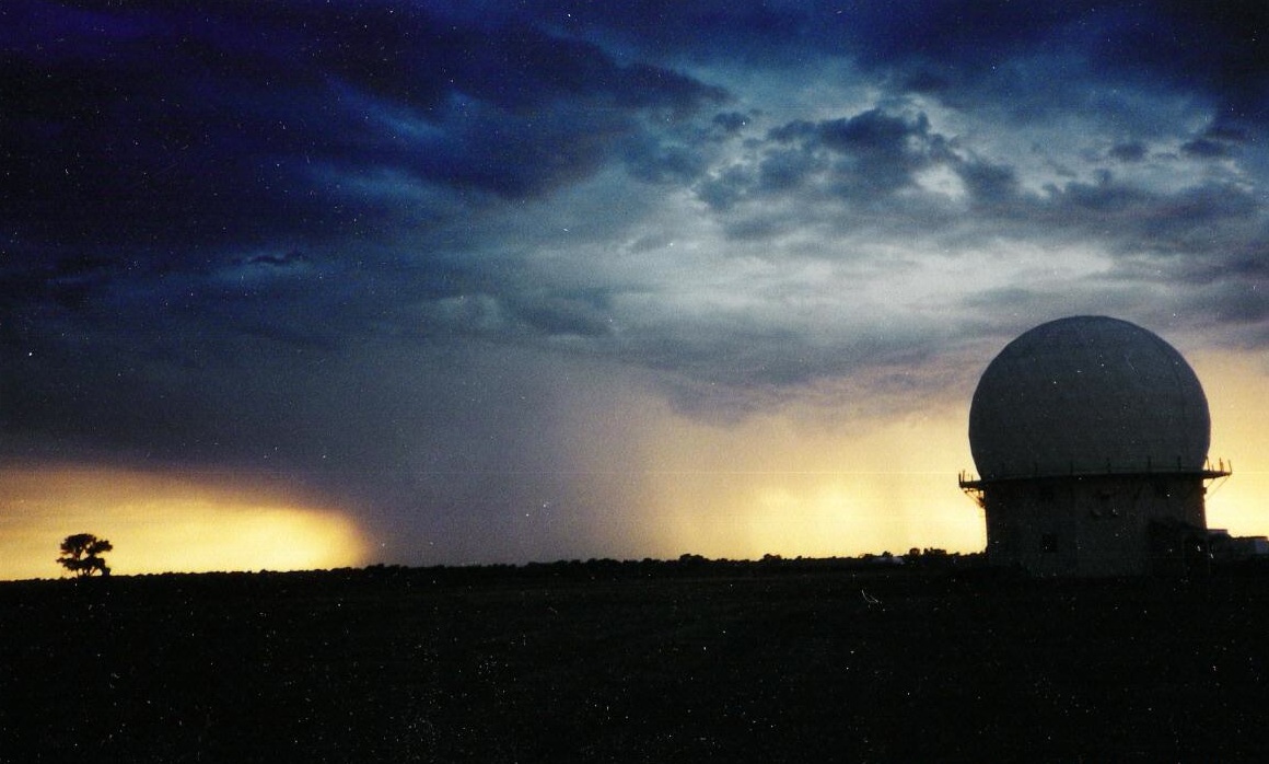 Photograph of a Doppler radar with a rain shaft behind it.